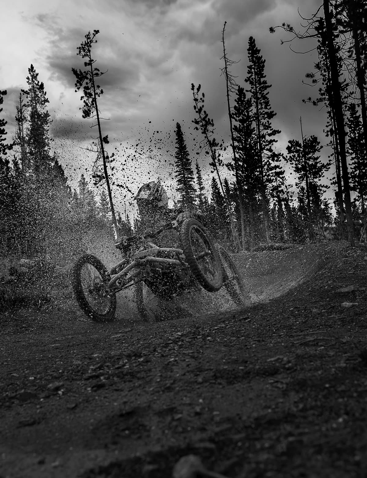 Black and white photograph of an adaptive rider throwing dirt through a turn
